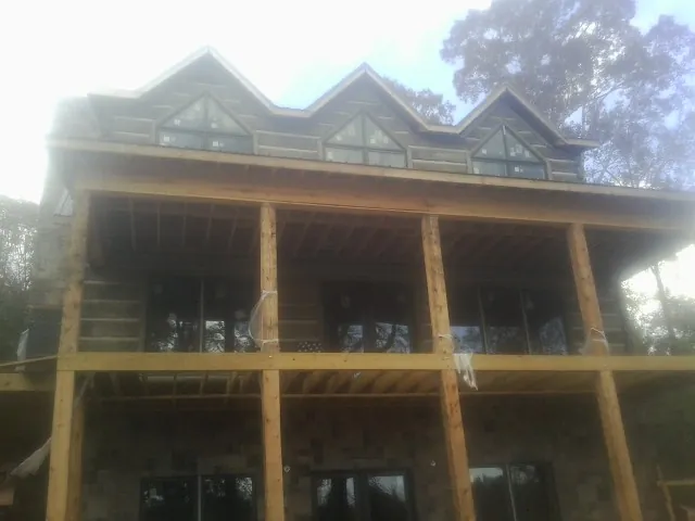 Dormers and porch framing on a large log home under construction — Roof Coating work by our crew in Ionia